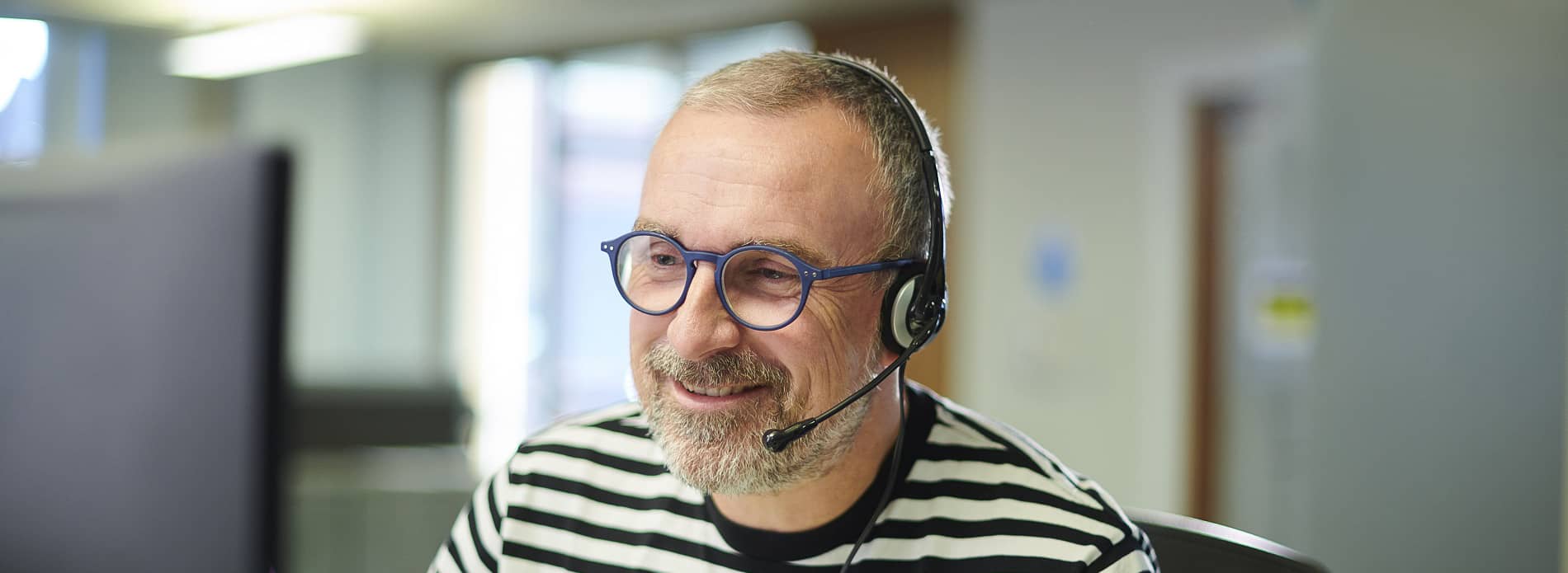 man in call centre with headset on speaking to customer