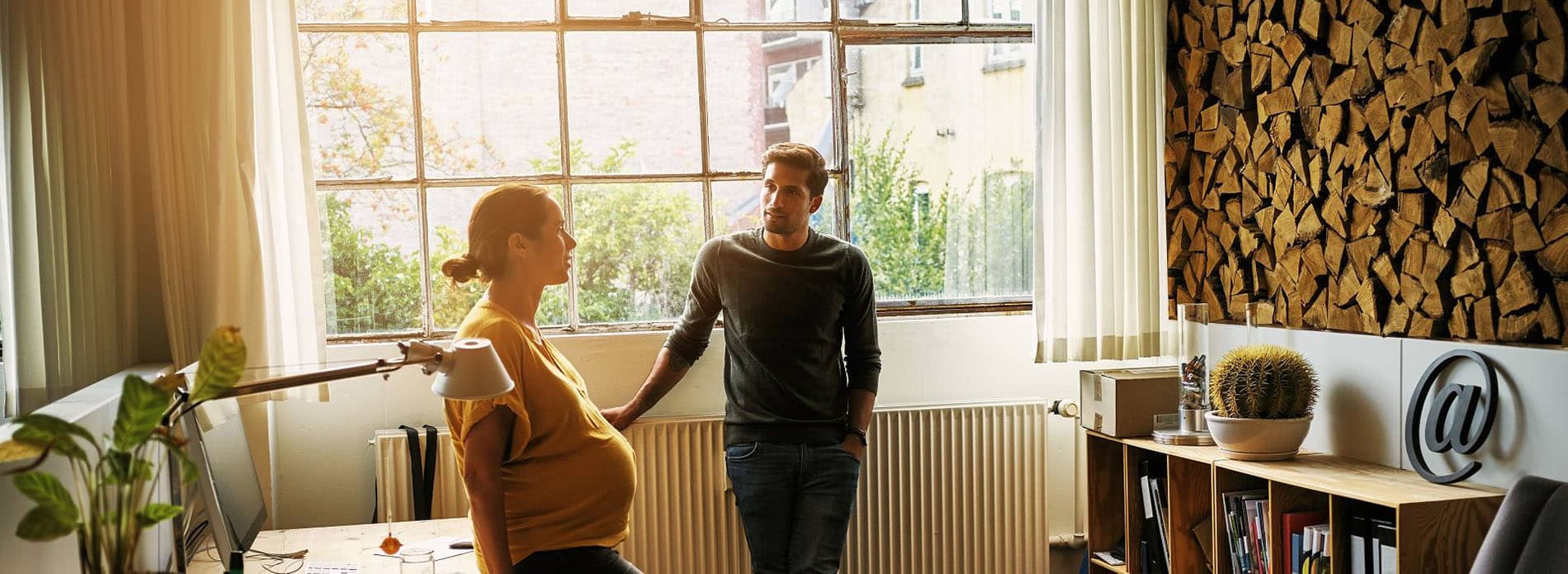 Expectant parents speaking in home office. 