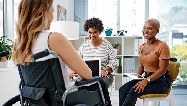 Two women talking to a woman in a wheelchair