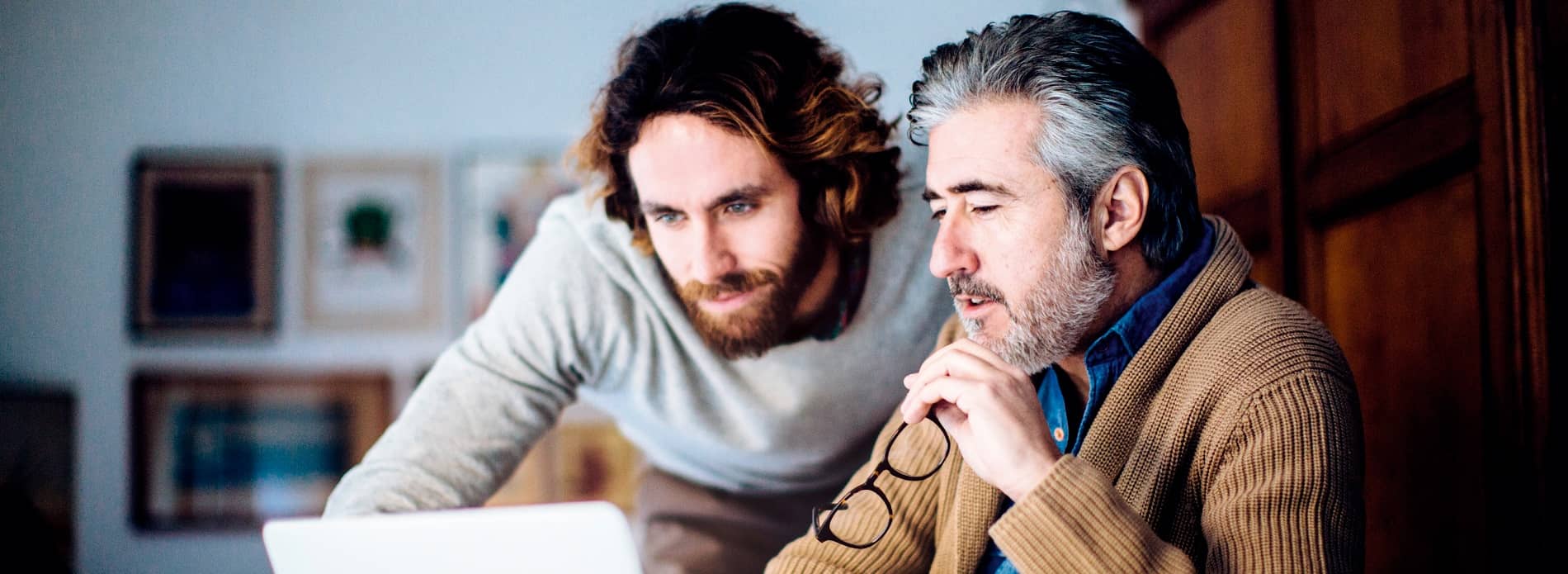 father and adult son looking at computer together
