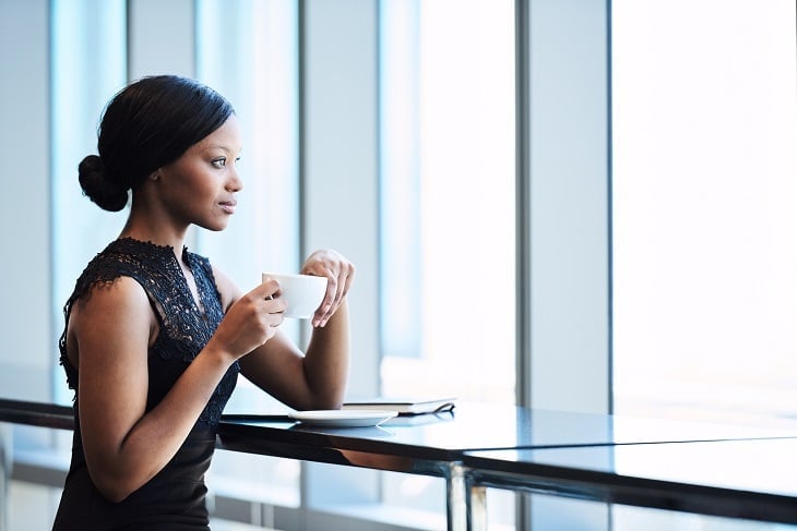 Woman drinking coffee and looking outside window