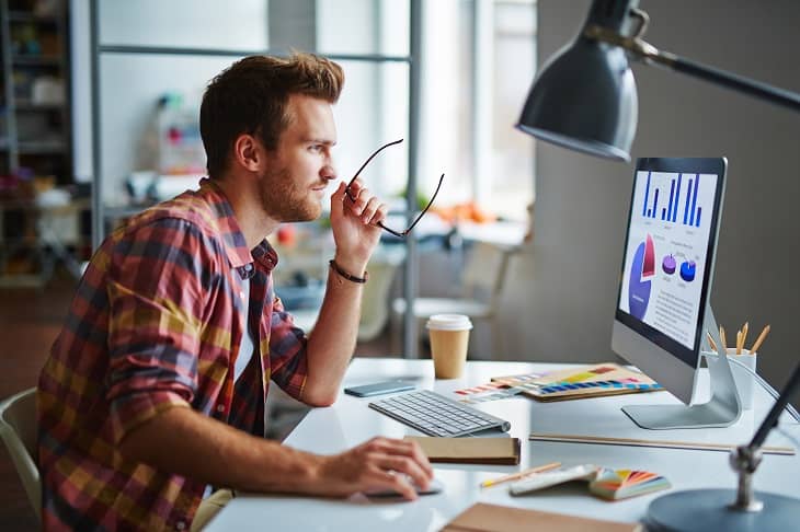 Man looking at graphs on a computer screen
