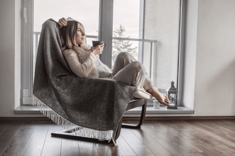 Woman drinking hot drink on arm chair