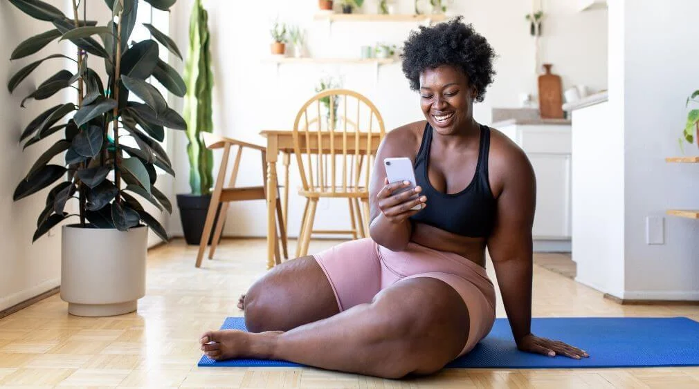 Woman checking her phone on a yoga mat